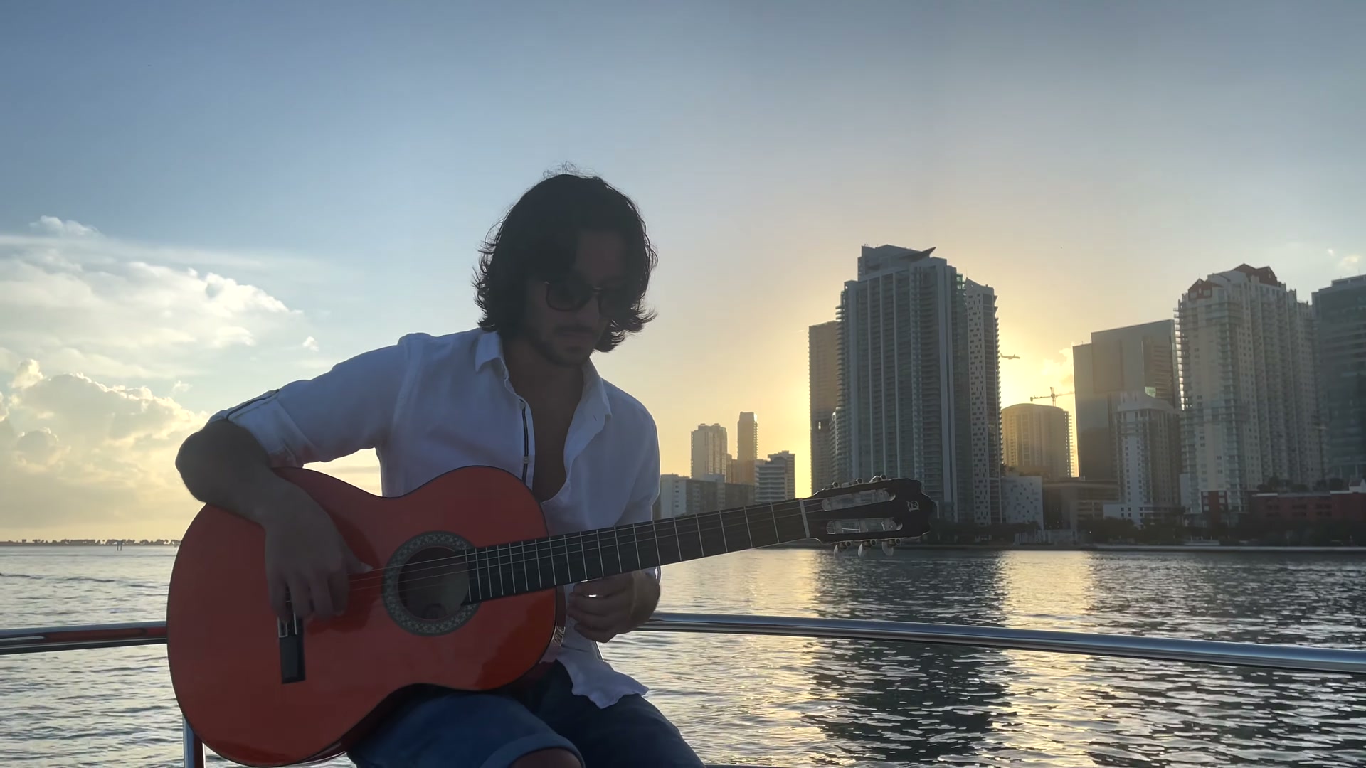 Sergio playing guitar on a yacht deck at sunset